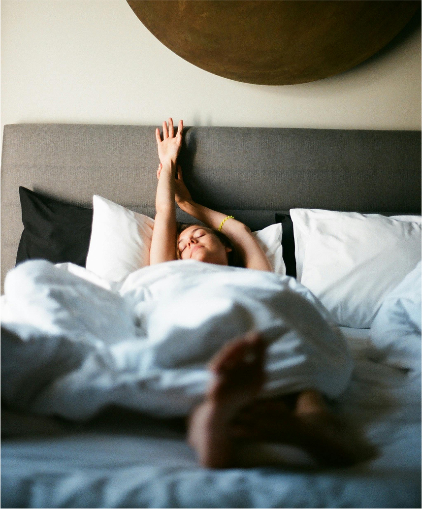 woman stretching sleeping in her bed